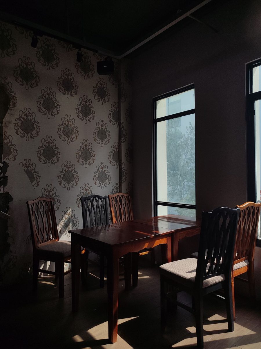 Dining corner with grey damask wallpaper, a dark wooden table and chairs in soft daylight