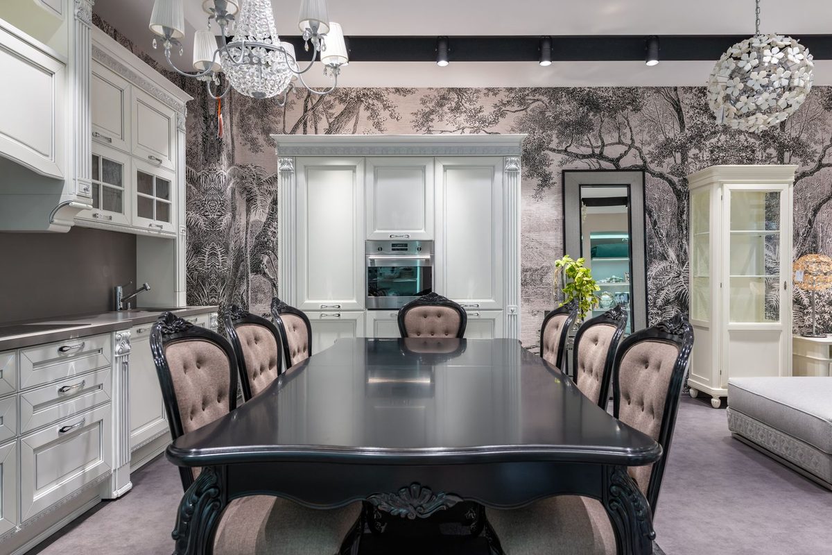 Open kitchen and dining space with a soft grey woodland mural wallpaper and a long dining table