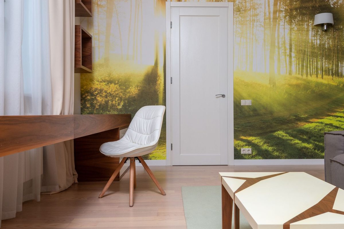 Reading nook with a bright forest-scene mural wallpaper, a desk and a modern chair