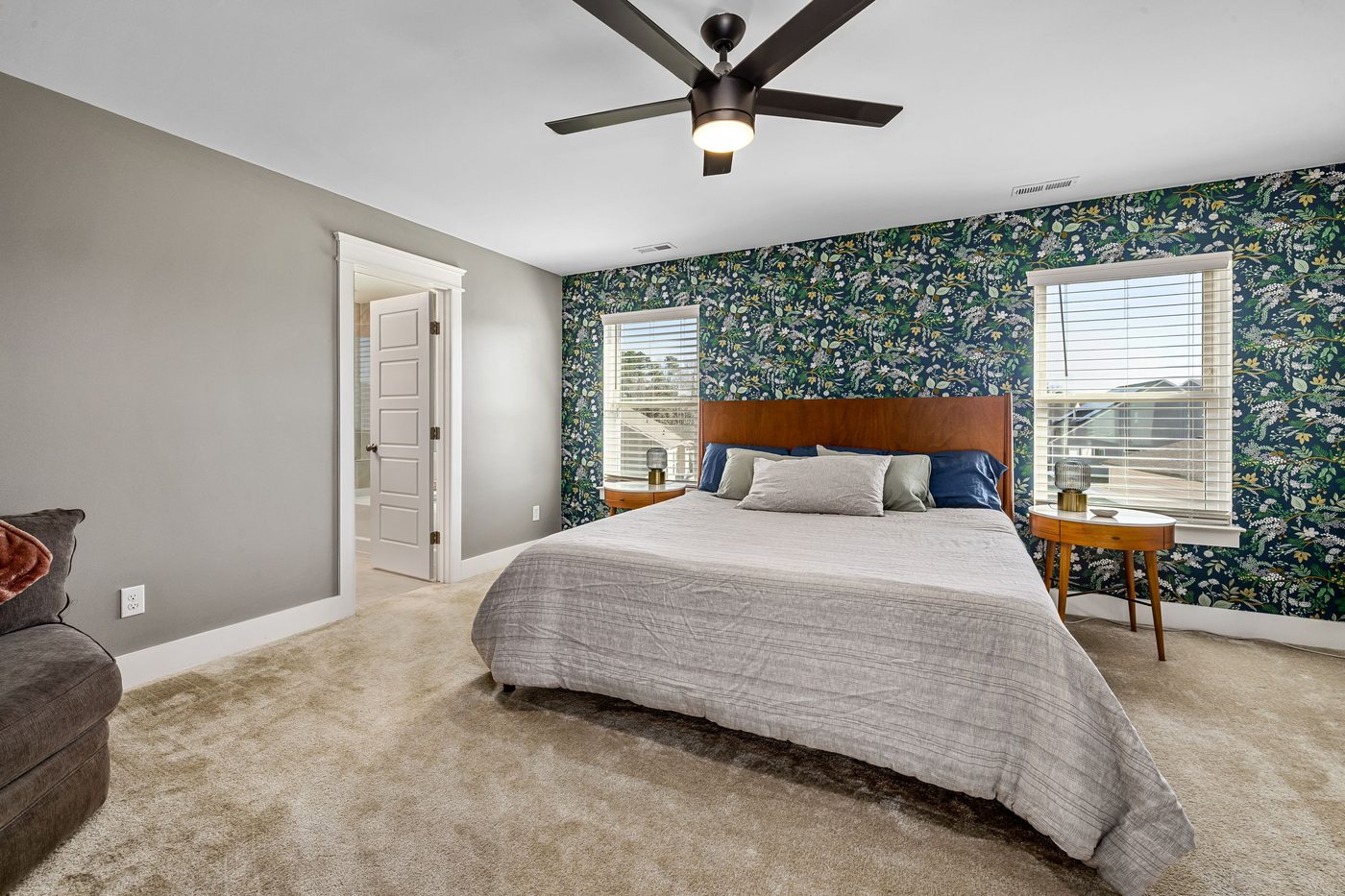 Bright bedroom with a green botanical accent wall behind the bed, framed by two windows