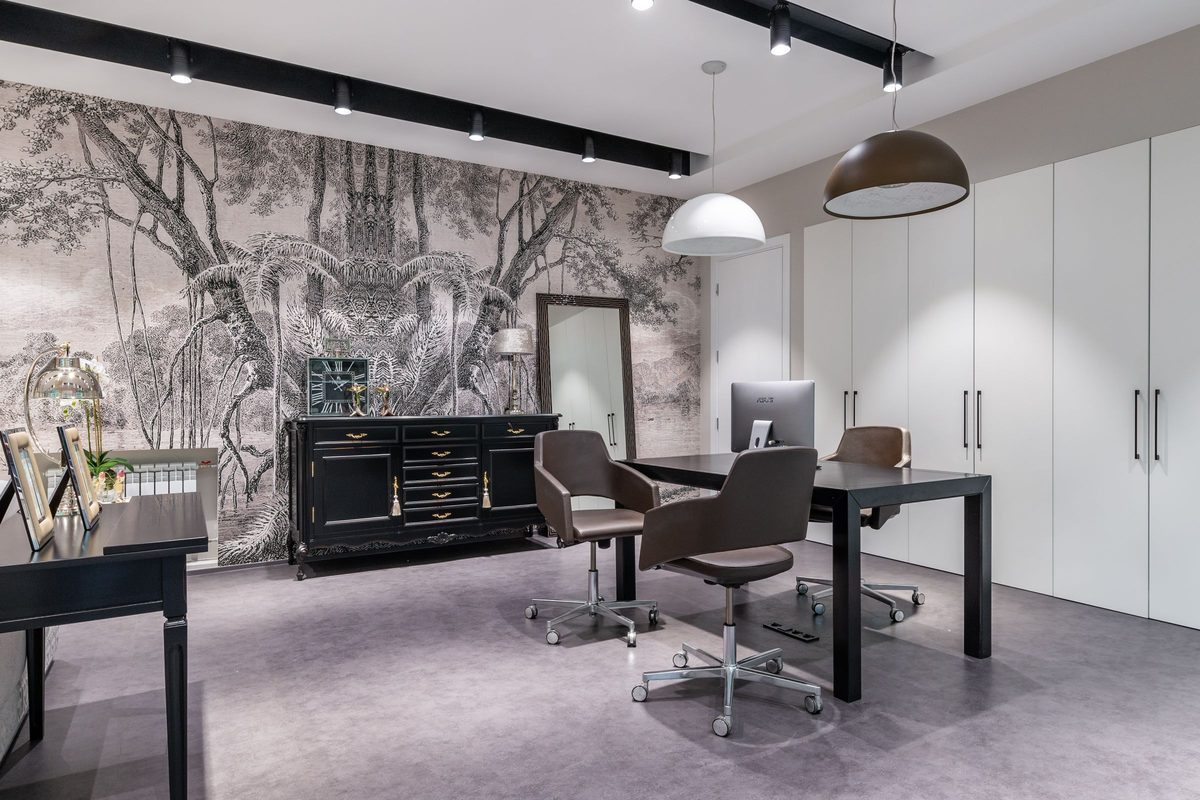 Refined home office with a detailed forest-scene mural wallpaper behind a dark desk and cabinetry